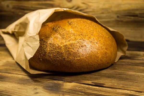Pan envasado en papel sobre mesa de madera — Foto de Stock