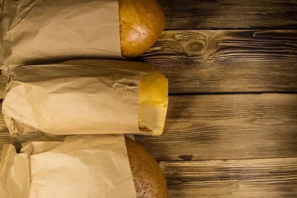 Surtido de pan envasado en papel sobre mesa de madera — Foto de Stock