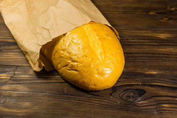 Pan envasado en papel sobre mesa de madera — Foto de Stock