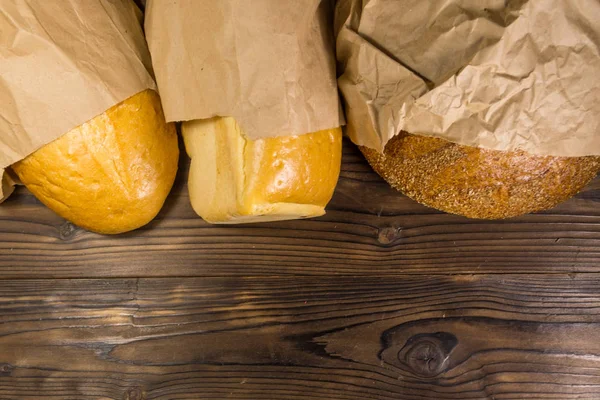 Surtido de pan envasado en papel sobre mesa de madera — Foto de Stock