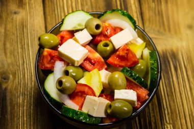 Ahşap masa üzerinde cam kapta Yunan salatası