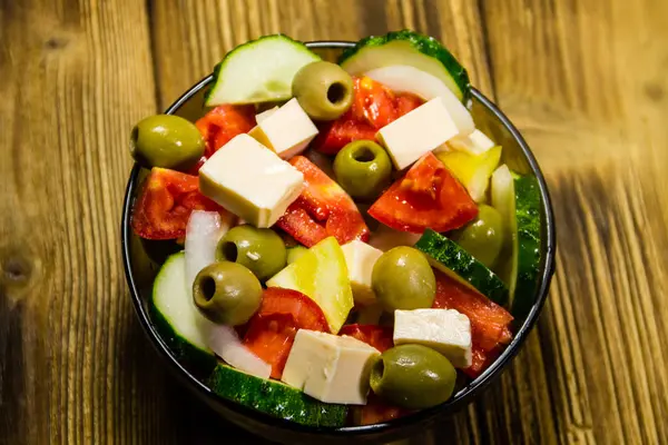 Salada grega em tigela de vidro na mesa de madeira — Fotografia de Stock