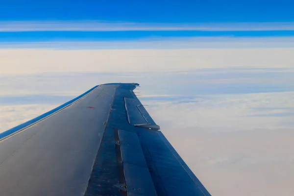 Ala de avião voando acima das nuvens no céu azul — Fotografia de Stock