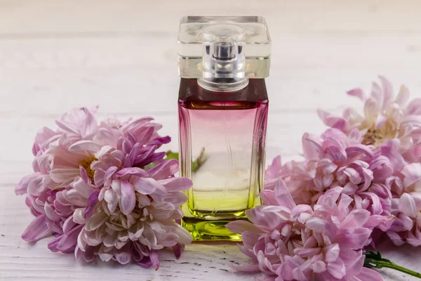 Femmes parfum avec des fleurs sur fond blanc en bois — Photo