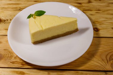 Ahşap masa beyaz bir tabağa lezzetli tatlı New York cheesecake parçası