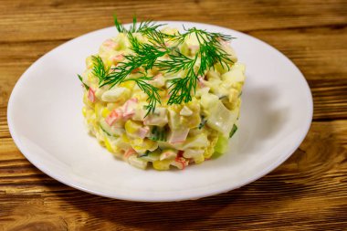 Yengeç çubuklu salata, tatlı mısır, salatalık, yumurta ve mayonez ahşap masada.