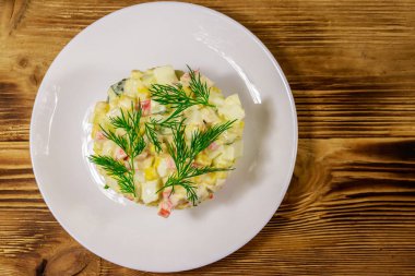 Yengeç çubuklu salata, tatlı mısır, salatalık, yumurta ve mayonez ahşap masada. Üst görünüm