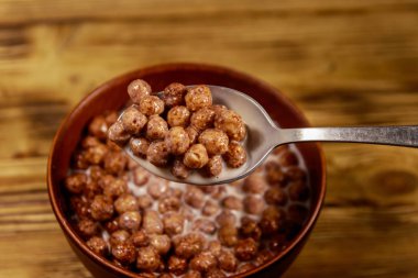 Ahşap masa üzerinde bir kase süt ile Tahıl çikolata topları. Kahvaltıile Kaşık