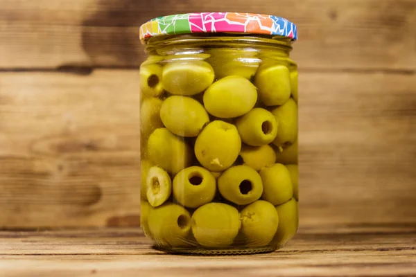 Aceitunas verdes en vinagre en frasco de vidrio sobre mesa de madera —  Fotos de Stock