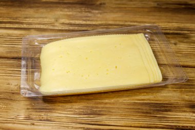 Tek kullanımlık plastik bir kutuda dilimler halinde peynir, ahşap bir masada.
