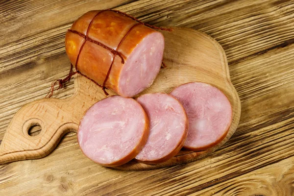 Sliced smoked sausage on cutting board on wooden table