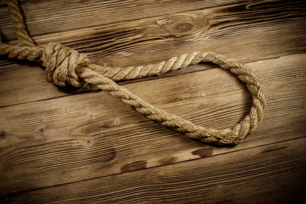 Tödliche Seilschleife auf einem hölzernen Hintergrund. Konzept der Todesstrafe oder Selbstmord — Stockfoto