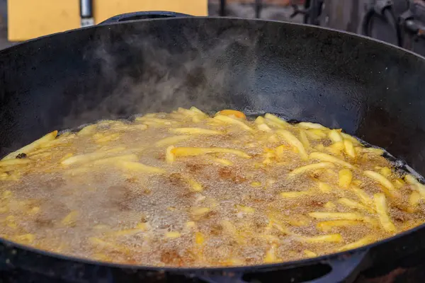 French fries cooking in a deep cast iron pan filled with oil — 스톡 사진