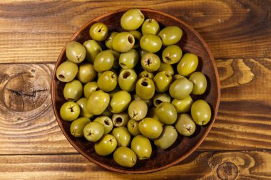 Ahşap masa üzerinde yeşil zeytin ile plaka