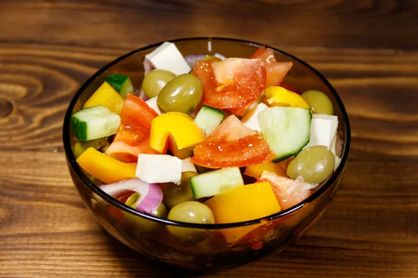 Salada grega em tigela de vidro na mesa de madeira — Fotografia de Stock