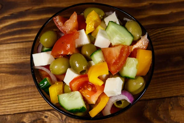 Salada grega em tigela de vidro na mesa de madeira — Fotografia de Stock