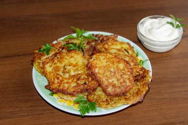 Ahşap masada ekşi kremalı ev yapımı patates krepleri.