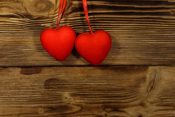 Dos corazones rojos colgando sobre fondo de madera — Foto de Stock