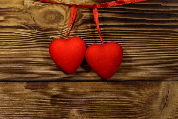 Два красных сердца висят на деревянном фоне — стоковое фото