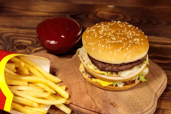 Delicioso hambúrguer grande com batatas fritas e ketchup na mesa de madeira — Fotografia de Stock