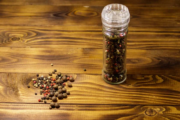 Agitateur de poivre en verre avec mélange de poivre de maïs sur fond en bois — Photo