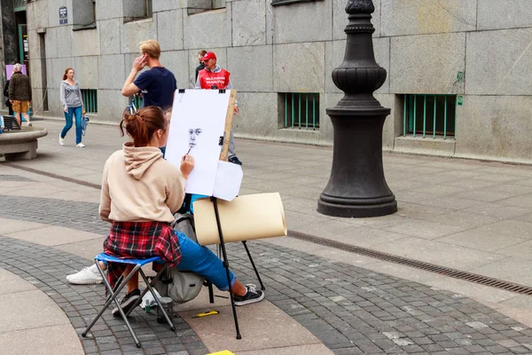 Девушка рисует картину на городской улице. Уличный художник рисует портрет девушки в центре Санкт-Петербурга, Россия — стоковое фото