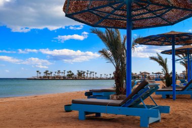 Tropik plajlarda güneş şemsiyeleri ve şezlonglar. Dinlenme, rahatlama, tatil, tatil