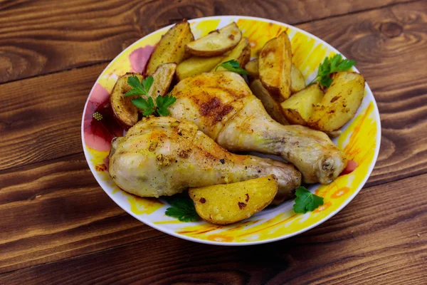 Baquetas de frango assadas com batatas em uma chapa na mesa de madeira — Fotografia de Stock