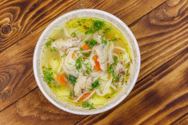 Tahta masada erişte ve sebze ile tavuk çorbası. Üstte görüntü