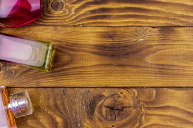 Ahşap arka planda farklı parfüm şişeleri. Üst görünüm, kopyalama alanı