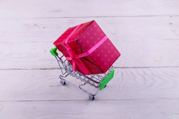 Carrito de compras con caja de regalo grande sobre fondo de madera blanco —  Fotos de Stock