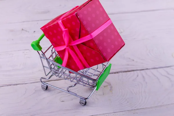 Kundvagn med stor presentbox på vit trä bakgrund — Stockfoto