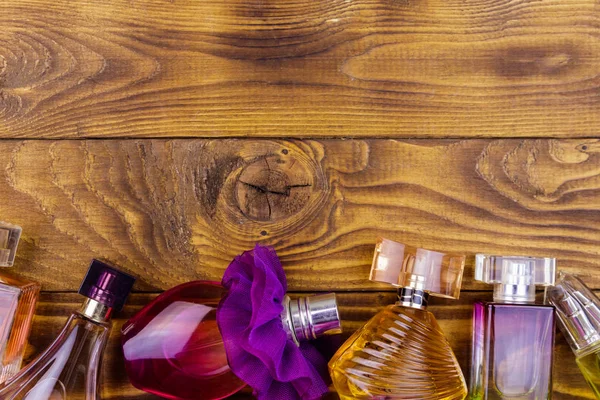 Different bottles of perfume on the wooden background. Top view, copy space — Stock Photo, Image