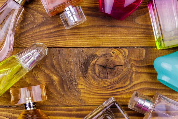Different bottles of perfume on the wooden background. Top view, copy space — Stock Photo, Image