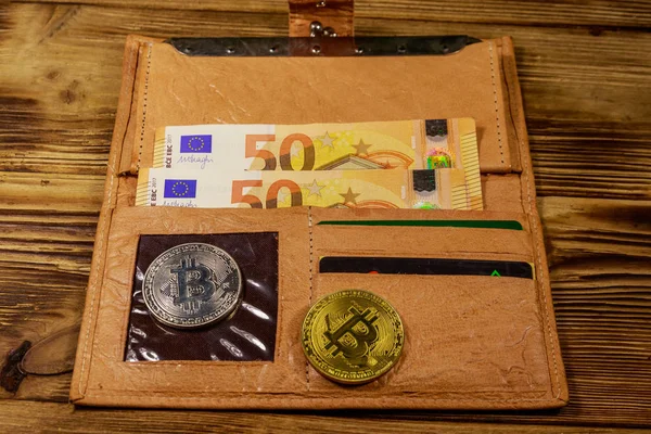 Pénztárca ötven euróval és bitcoinnal fából készült háttérrel — Stock Fotó