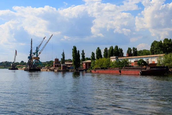 Heavy cranes in cargo port on the riverbank — Stock Photo, Image