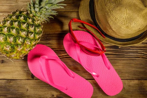 Sommerferienkonzept. Ananas, Strohhut, Flip-Flops und Sonnenbrille auf Holzgrund — Stockfoto