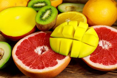 Ahşap masa üzerinde tropikal meyve çeşitleri. Muz, mango, portakal, avokado, greyfurt ve kivi ile natürmort