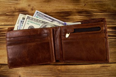 Ahşap masanın üzerinde Amerikan doları olan açık cüzdan. Üstte görüntü