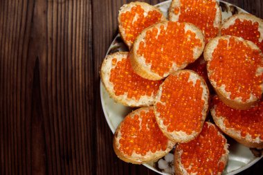 Tereyağlı sandviç ve ahşap masada kırmızı havyar.