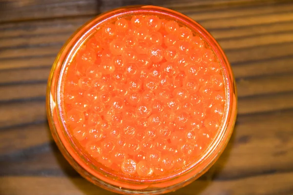 Röd kaviar i glasburk på träbord — Stockfoto