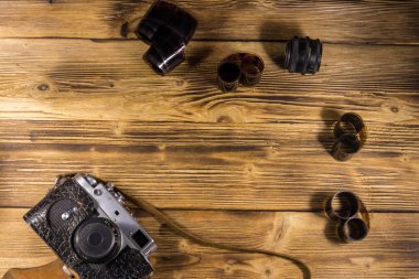 Ahşap masanın üzerinde fotoğraf makinesi ve lens olan eski fotoğraf makinesi.