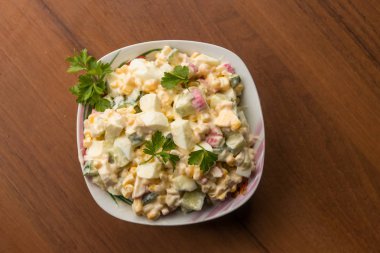 Yengeç çubuklu salata, tatlı mısır, salatalık, yumurta ve mayonez ahşap masada. Üst görünüm