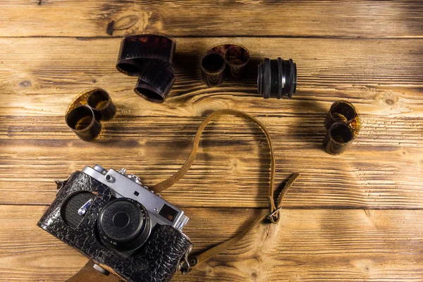 Retro photo camera with photo film and lens on wooden table — Stock Photo, Image