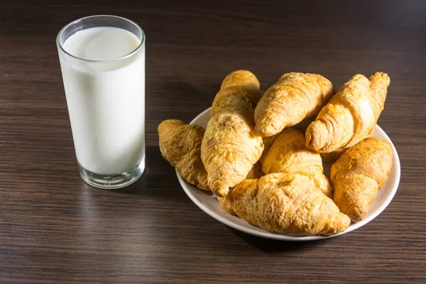 Copo de leite e croissants frescos na mesa de madeira — Fotografia de Stock