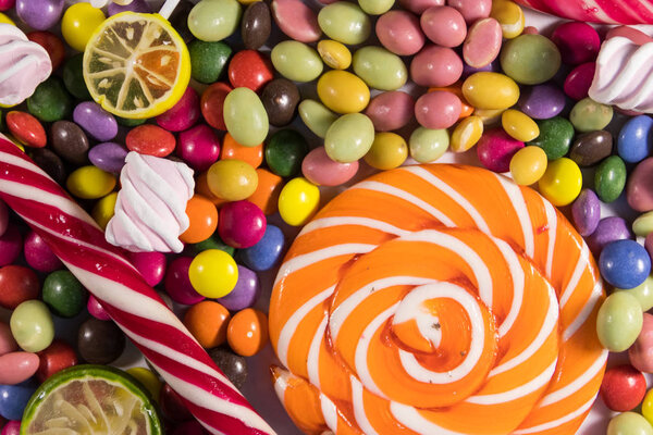 Background of colorful chocolate candies, lollipops, candy cane and marshmallows