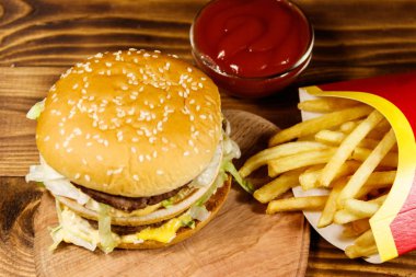 Tahta masada patates kızartması ve ketçaplı leziz büyük hamburger.