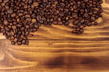 Ahşap arka planda kavrulmuş kahve çekirdekleri.