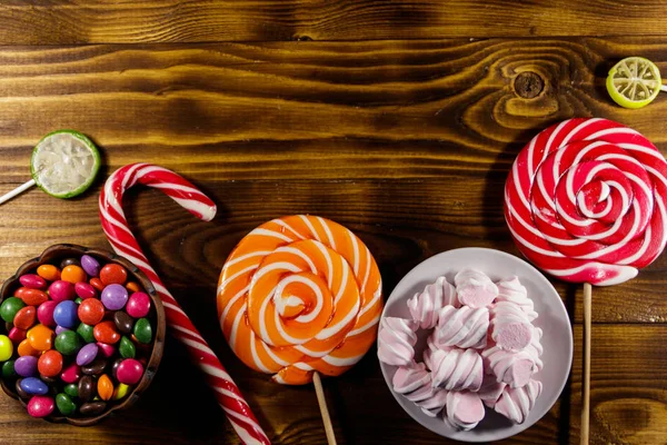 Барвисті шоколадні цукерки, льодяники, цукерки тростина і зефір на дерев'яному столі — стокове фото