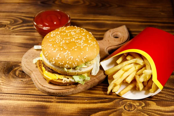 Delizioso hamburger grande con patatine fritte e ketchup sul tavolo di legno — Foto Stock